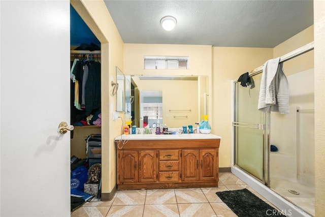 bathroom featuring vanity, a textured ceiling, tile patterned floors, and a shower with shower door