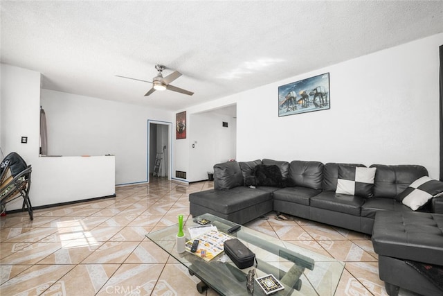 living room featuring ceiling fan, light tile patterned floors, and a textured ceiling