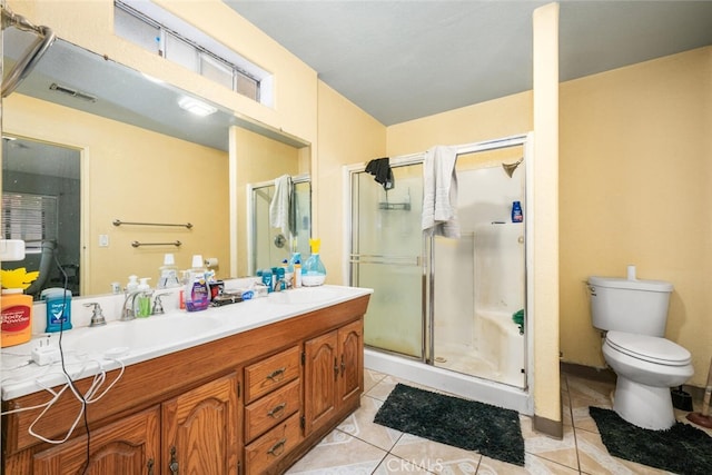 bathroom with tile patterned floors, vanity, toilet, and a shower with door