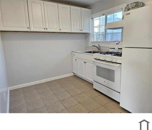 kitchen with white appliances, light tile patterned floors, sink, and white cabinets