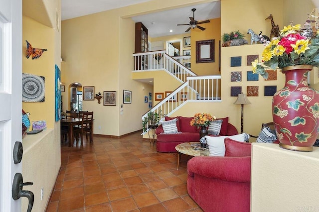 living room with tile patterned flooring, ceiling fan, and a towering ceiling