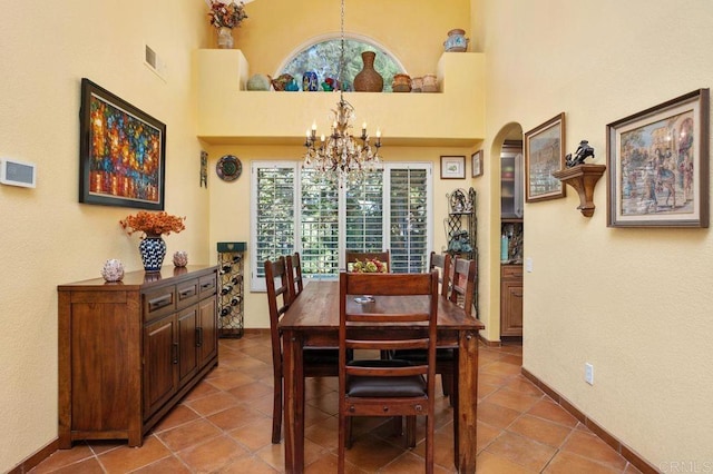 dining area with a chandelier, a high ceiling, light tile patterned floors, and a wealth of natural light