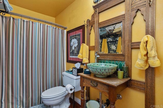 bathroom featuring a shower with curtain, sink, and toilet