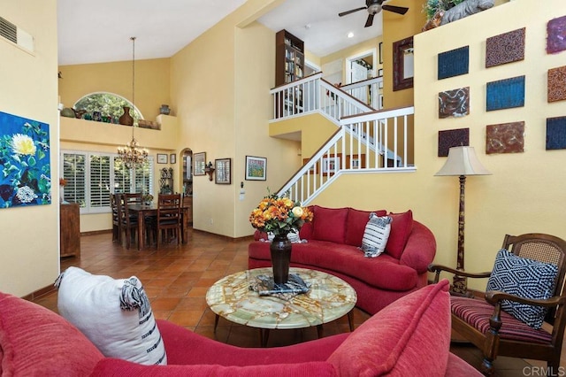 living room featuring tile patterned floors, ceiling fan with notable chandelier, and a high ceiling