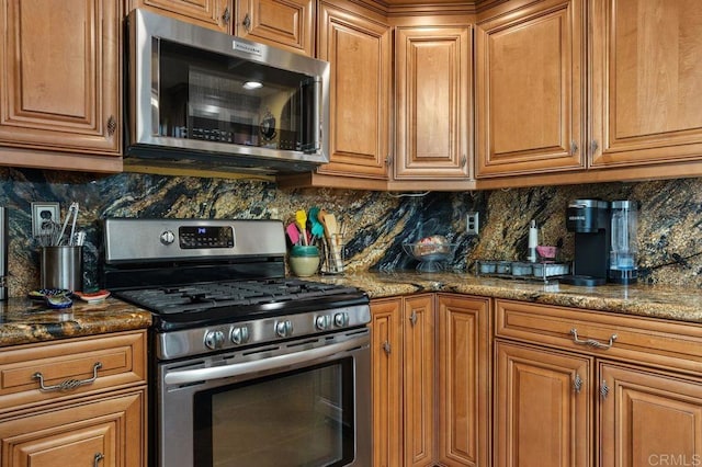 kitchen featuring decorative backsplash, appliances with stainless steel finishes, and dark stone counters