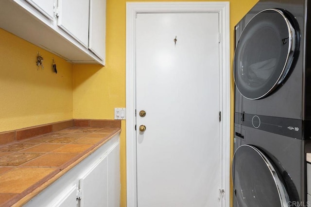 laundry room with stacked washer / dryer and cabinets