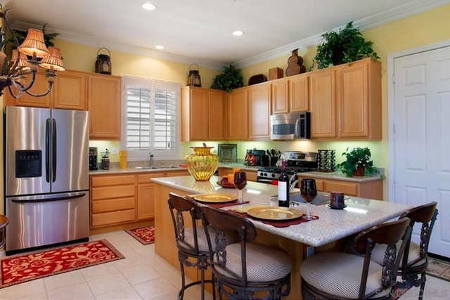 kitchen featuring crown molding, appliances with stainless steel finishes, a kitchen island with sink, and light brown cabinets