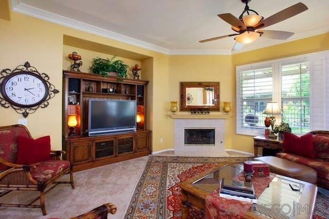 living room featuring ceiling fan, light carpet, ornamental molding, and a tile fireplace