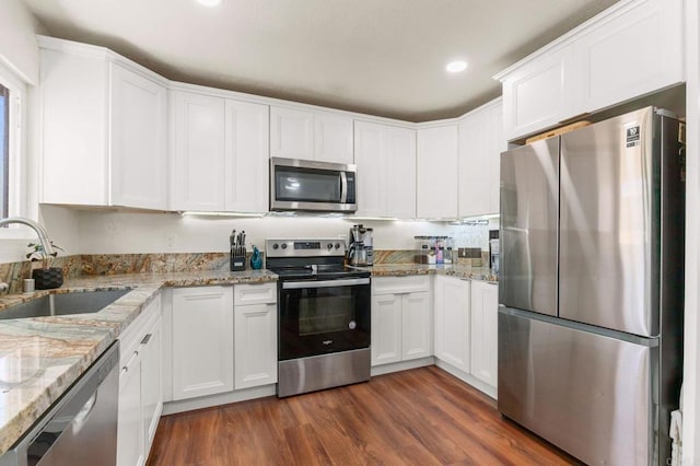 kitchen featuring dark hardwood / wood-style floors, sink, white cabinetry, appliances with stainless steel finishes, and light stone counters