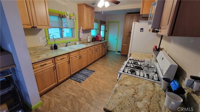 kitchen with white appliances, light stone countertops, ceiling fan, and a sink