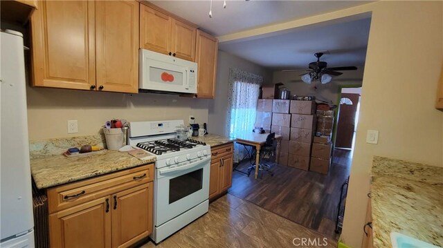 kitchen with light stone counters, white appliances, and ceiling fan