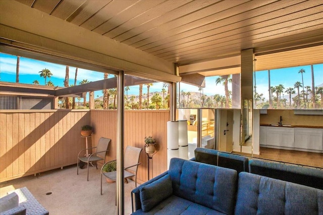 sunroom featuring plenty of natural light, wooden ceiling, and sink