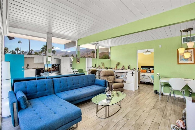 living room featuring beamed ceiling, sink, and light hardwood / wood-style flooring