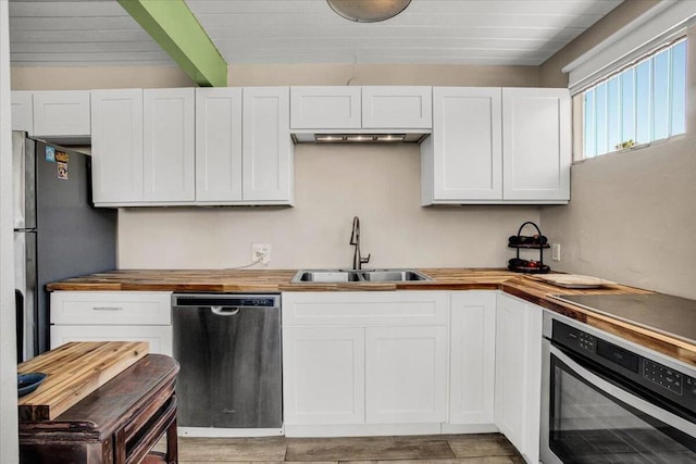 kitchen with butcher block counters, white cabinetry, sink, and stainless steel appliances