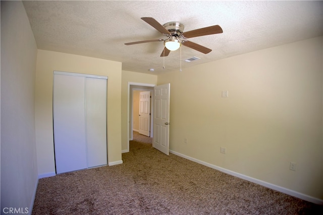 unfurnished bedroom with carpet, a textured ceiling, a closet, and ceiling fan