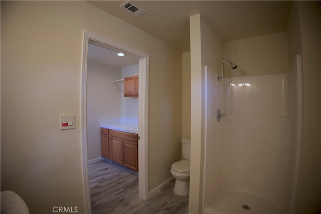 bathroom with vanity, toilet, hardwood / wood-style flooring, and walk in shower