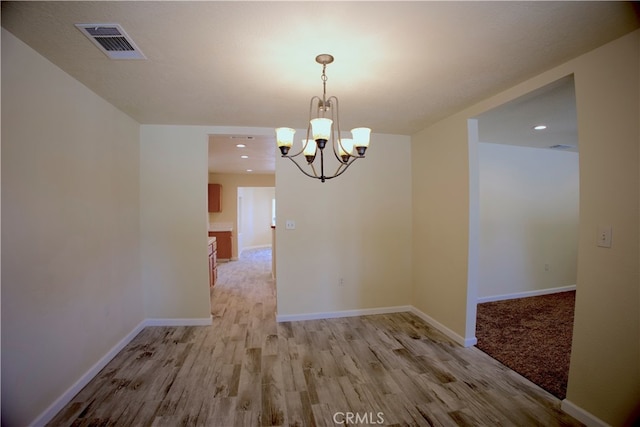 unfurnished dining area featuring light hardwood / wood-style floors and an inviting chandelier