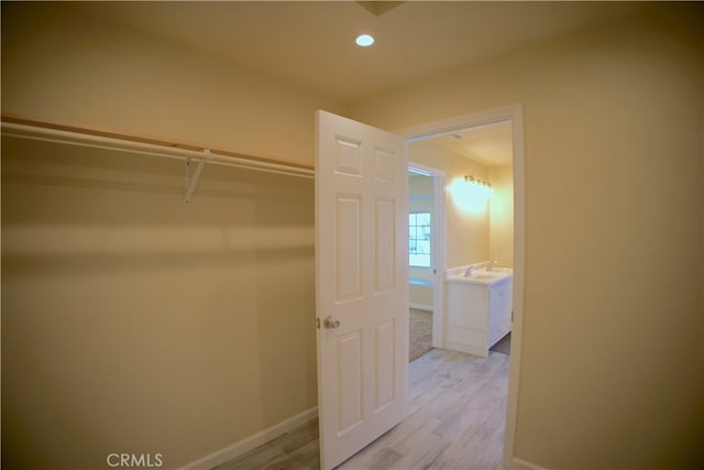 walk in closet with light hardwood / wood-style flooring