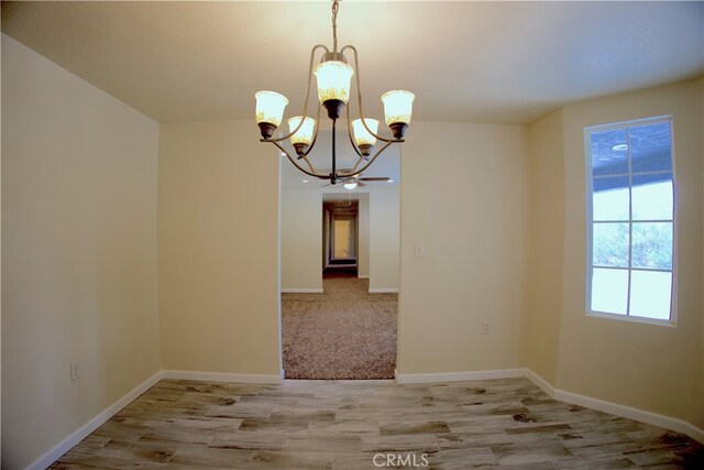 unfurnished dining area featuring light wood-type flooring and an inviting chandelier