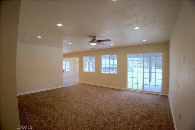 spare room featuring ceiling fan, a textured ceiling, carpet floors, and plenty of natural light