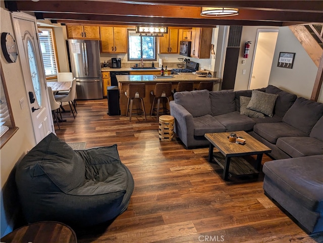 living room featuring beamed ceiling, sink, and dark hardwood / wood-style flooring