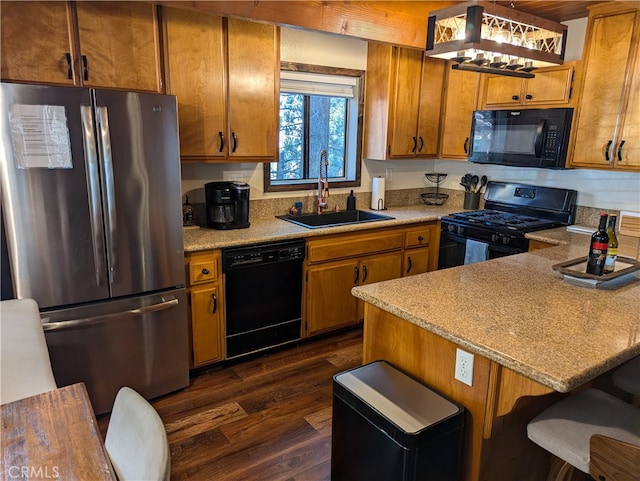 kitchen featuring dark hardwood / wood-style floors, black appliances, sink, and a breakfast bar area