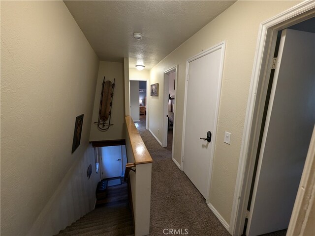 hall with dark colored carpet and a textured ceiling