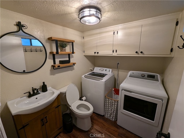 bathroom featuring a textured ceiling, wood-type flooring, toilet, sink, and washer and clothes dryer