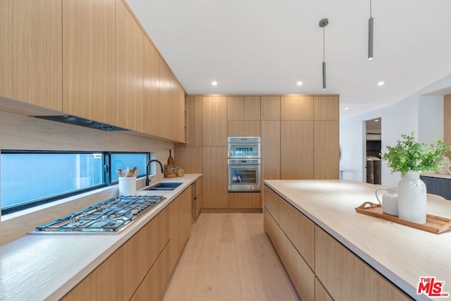 kitchen with light hardwood / wood-style floors, hanging light fixtures, stainless steel double oven, sink, and light brown cabinets