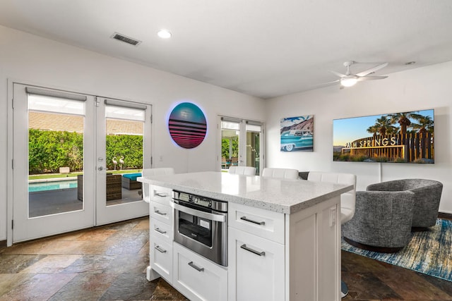 kitchen featuring french doors, a healthy amount of sunlight, white cabinetry, and stainless steel oven