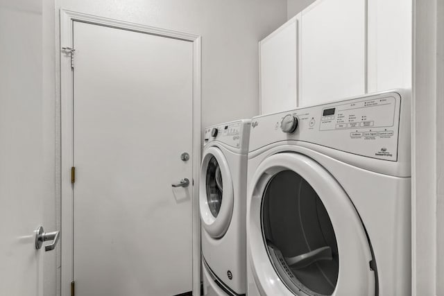 clothes washing area with independent washer and dryer and cabinets