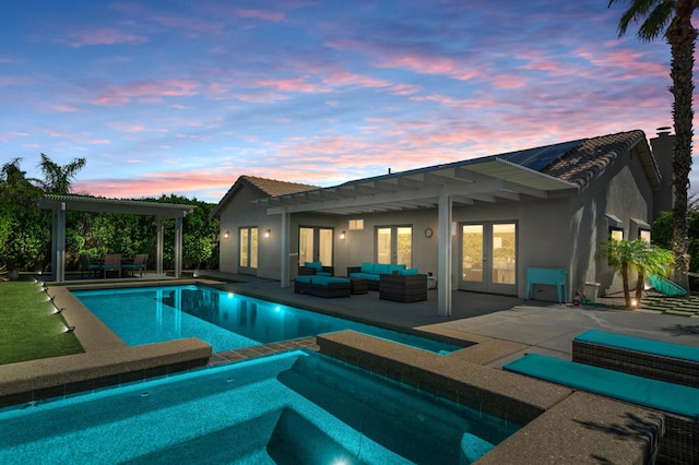 pool at dusk featuring an in ground hot tub, an outdoor living space, and a patio