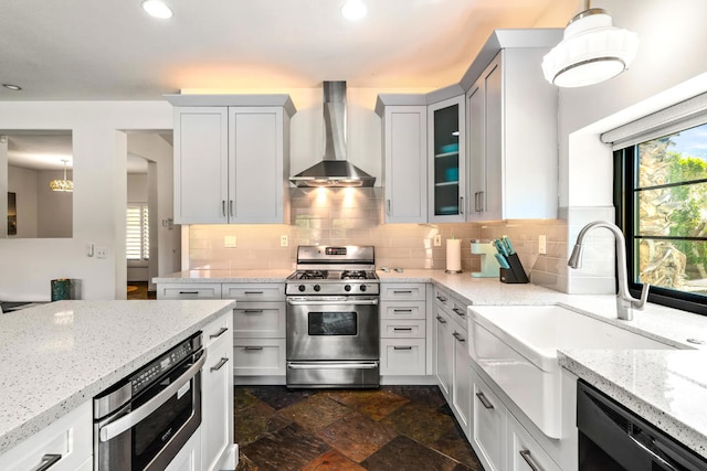 kitchen featuring appliances with stainless steel finishes, hanging light fixtures, wall chimney exhaust hood, white cabinets, and light stone counters