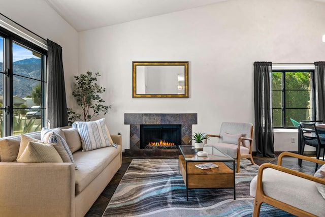 living room with hardwood / wood-style flooring, vaulted ceiling, a wealth of natural light, and a tile fireplace