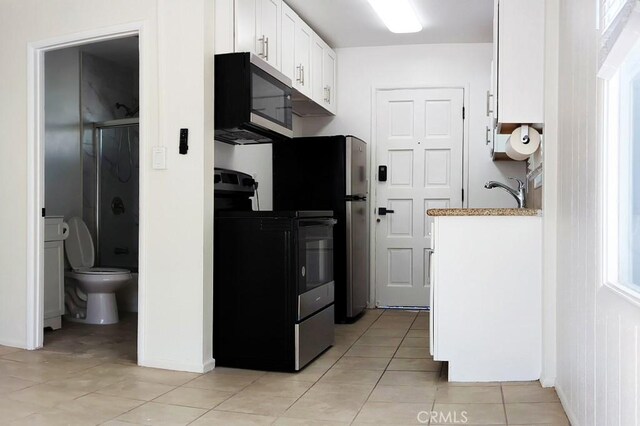 kitchen featuring white cabinetry, black range, and light tile patterned floors