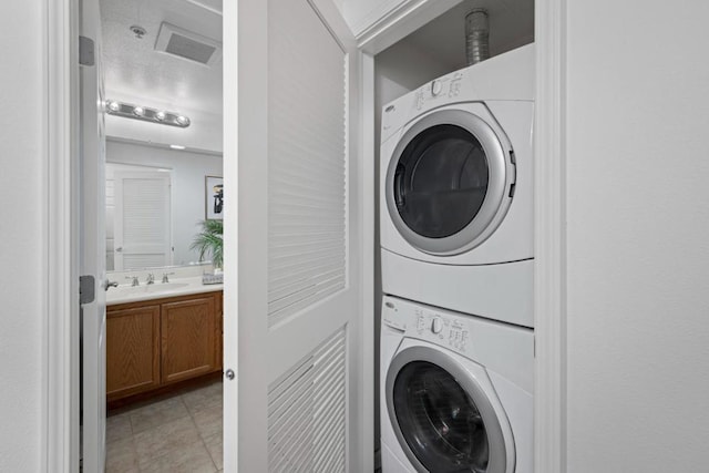 clothes washing area with stacked washing maching and dryer and sink