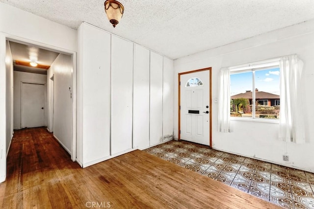 foyer entrance with wood-type flooring and a textured ceiling