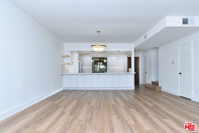 unfurnished living room with light wood-type flooring and an inviting chandelier