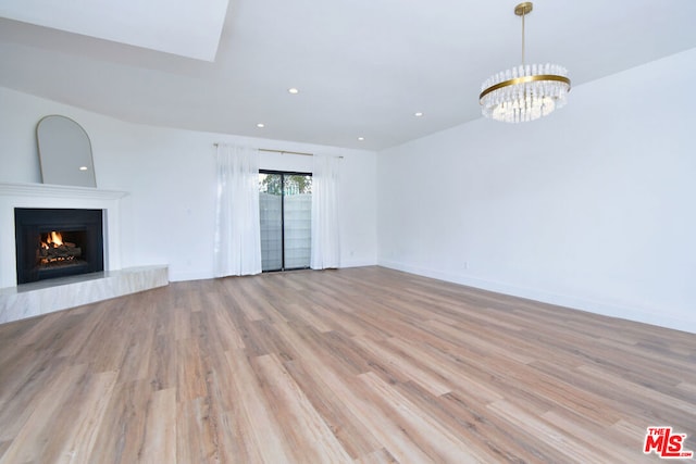 unfurnished living room with light wood-type flooring and a chandelier