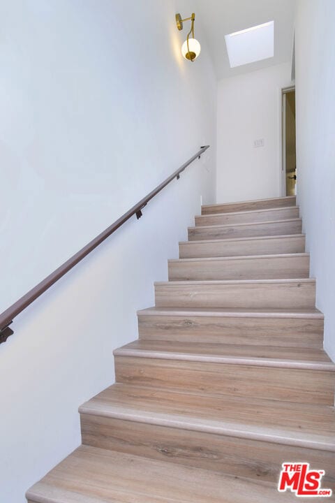 stairway featuring vaulted ceiling with skylight