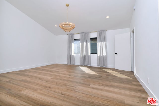 unfurnished room featuring light hardwood / wood-style flooring, lofted ceiling, and a notable chandelier