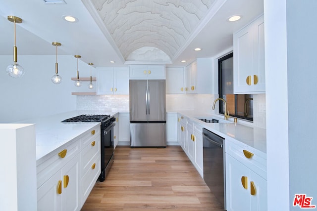 kitchen with white cabinets, decorative light fixtures, appliances with stainless steel finishes, and light hardwood / wood-style flooring