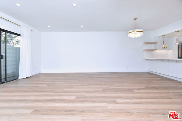 unfurnished room with light hardwood / wood-style floors and an inviting chandelier