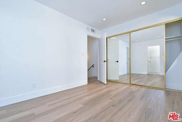 unfurnished bedroom with a closet and light hardwood / wood-style flooring