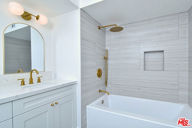 bathroom with tiled shower / bath combo and vanity