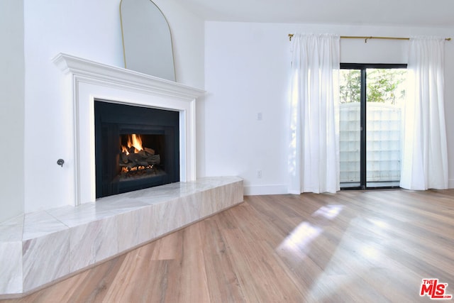 unfurnished living room with light wood-type flooring and a tile fireplace