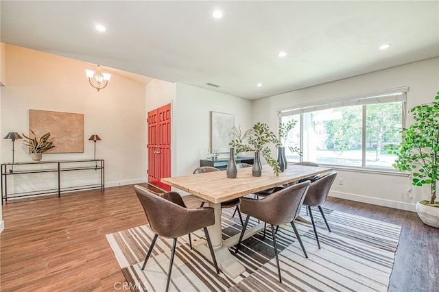 dining area with wood-type flooring and an inviting chandelier