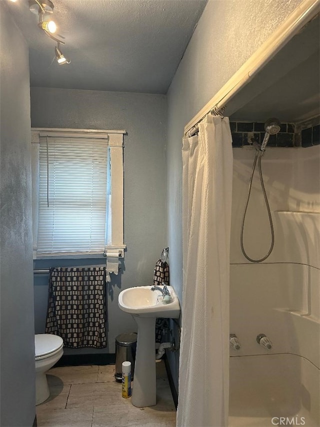 bathroom featuring toilet, a textured ceiling, and a shower with shower curtain