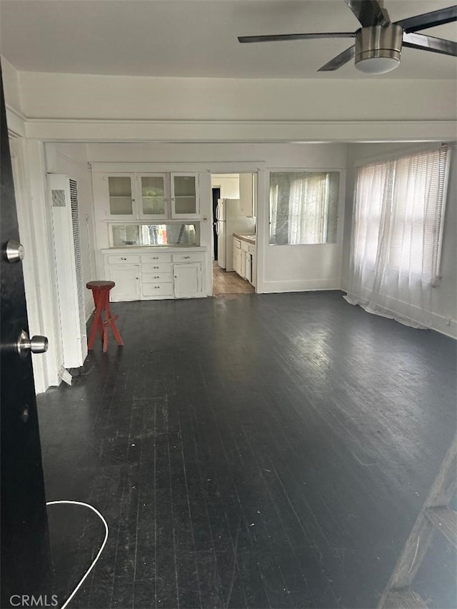 unfurnished living room with dark wood-type flooring and ceiling fan