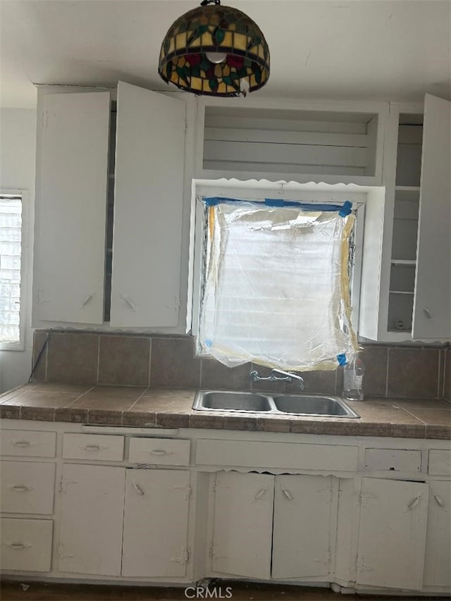 kitchen with tile counters, white cabinets, and sink